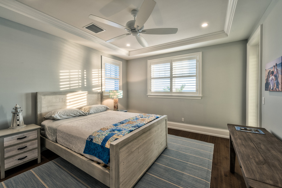 Design ideas for a large beach style guest bedroom in Miami with grey walls and dark hardwood floors.
