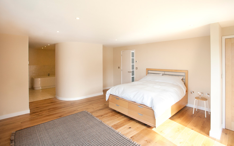 Photo of a mid-sized contemporary master bedroom in Cornwall with beige walls, medium hardwood floors, no fireplace and brown floor.