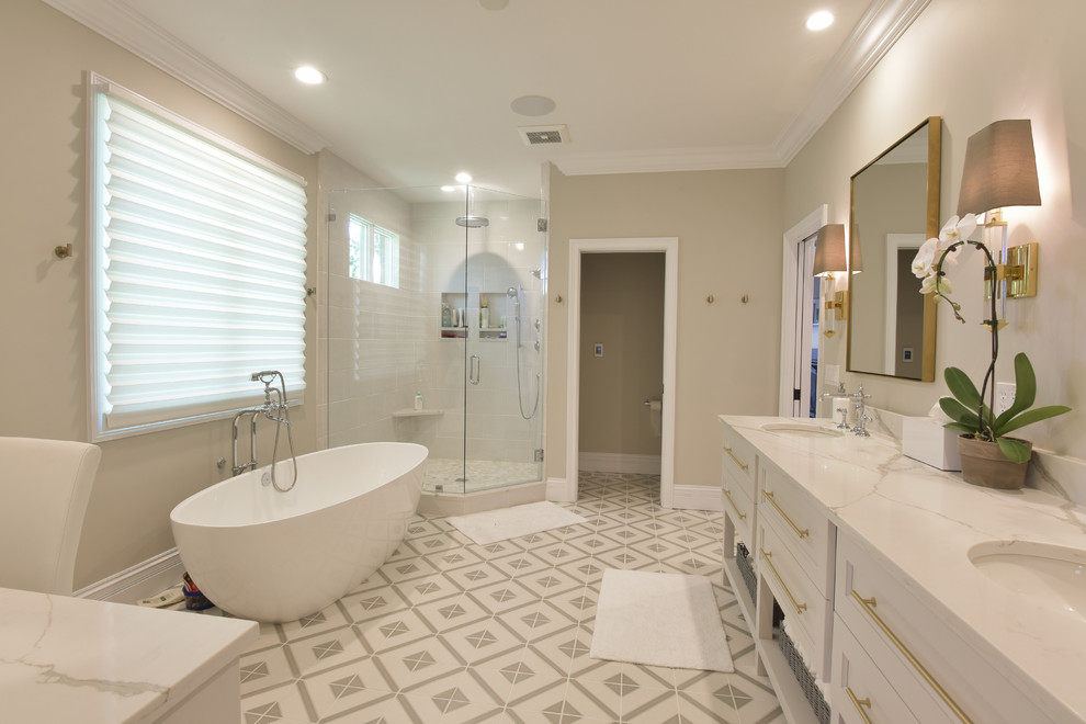 Design ideas for a mid-sized transitional master bathroom in St Louis with recessed-panel cabinets, white cabinets, a freestanding tub, a corner shower, white tile, porcelain tile, beige walls, cement tiles, an undermount sink, marble benchtops, multi-coloured floor and a hinged shower door.