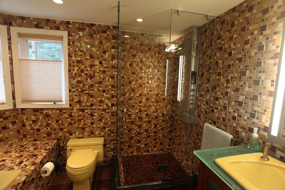 This is an example of a mid-sized contemporary 3/4 bathroom in New York with glass-front cabinets, dark wood cabinets, a drop-in tub, an alcove shower, multi-coloured tile, mosaic tile, multi-coloured walls, porcelain floors, a drop-in sink, glass benchtops, black floor and a hinged shower door.