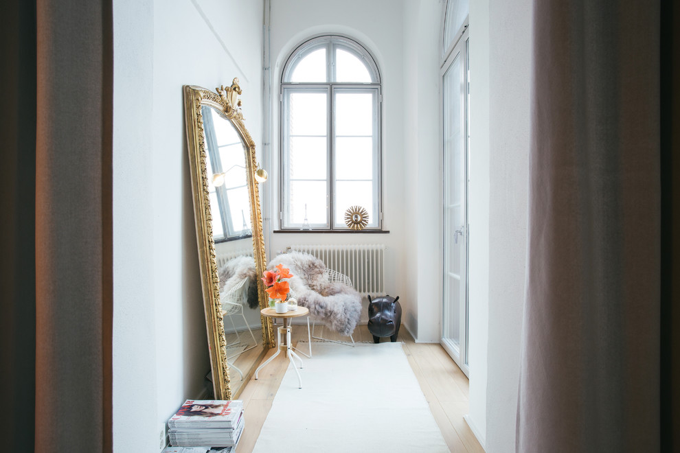 Design ideas for a mid-sized scandinavian hallway in Stockholm with white walls and light hardwood floors.