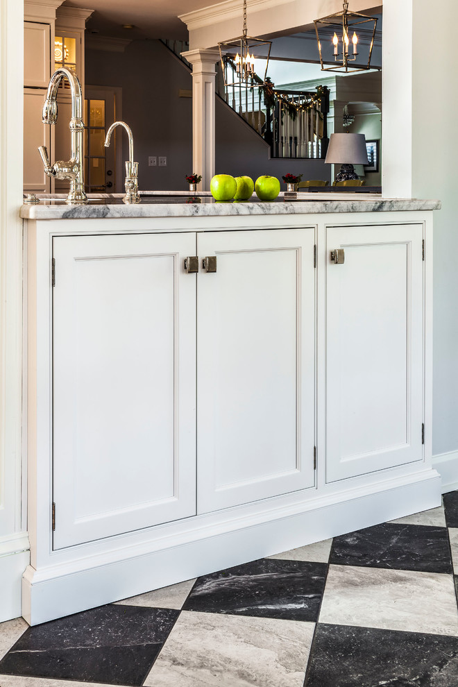 This is an example of a small transitional single-wall wet bar in Baltimore with white cabinets, quartzite benchtops, porcelain floors, multi-coloured floor, an undermount sink, shaker cabinets and grey benchtop.