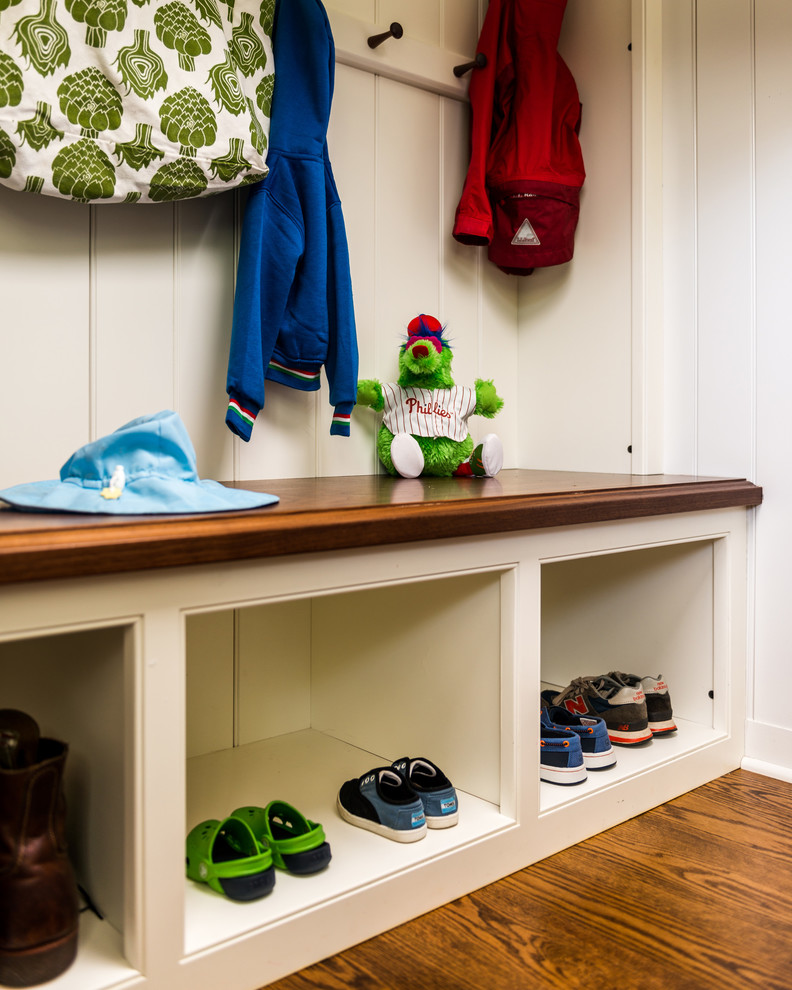 Country mudroom in Philadelphia with white walls and medium hardwood floors.