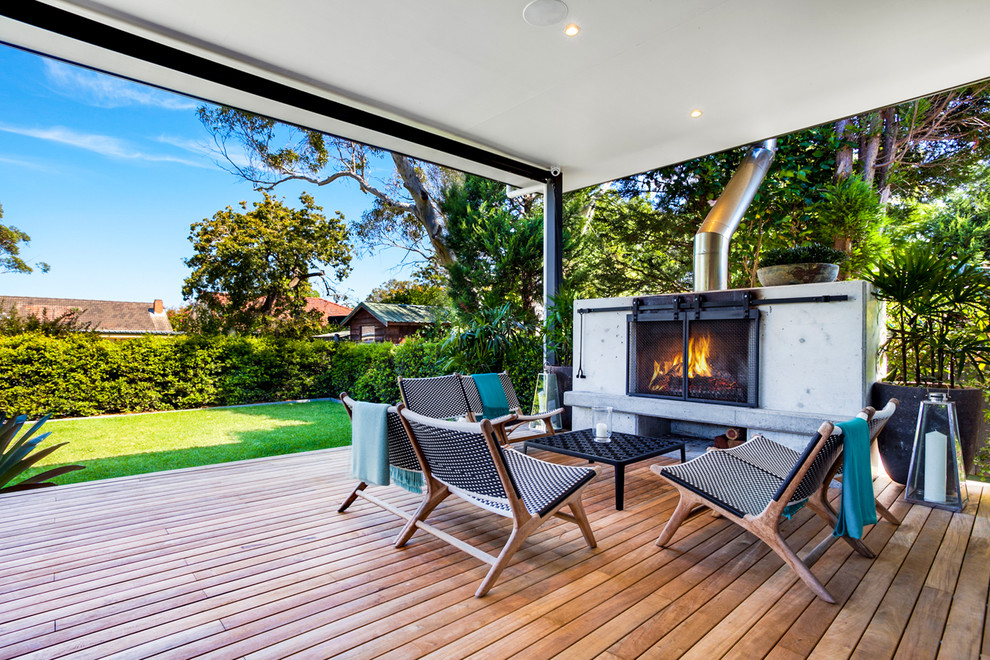 Photo of a mid-sized contemporary backyard deck in Sydney with a fire feature and a roof extension.