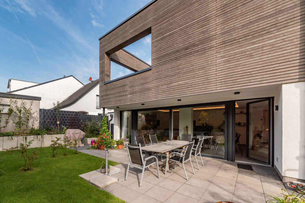 Diseño de fachada de casa moderna de tamaño medio de tres plantas con revestimientos combinados, tejado plano y tablilla
