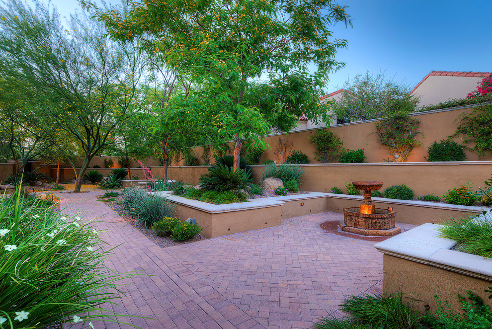Design ideas for a large mediterranean backyard partial sun garden in Phoenix with a water feature and brick pavers.
