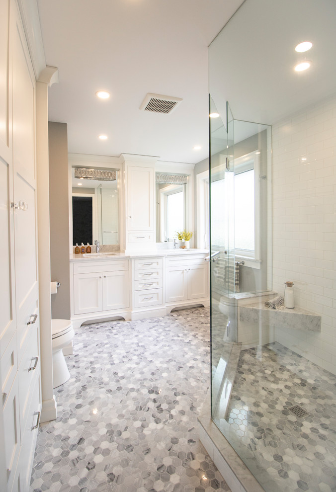 Large transitional master bathroom in Other with shaker cabinets, white cabinets, a corner shower, a two-piece toilet, white tile, subway tile, white walls, marble floors, an undermount sink, engineered quartz benchtops, white floor, a hinged shower door and white benchtops.