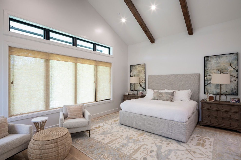 На фото: хозяйская спальня с белыми стенами, светлым паркетным полом, коричневым полом и балками на потолке с