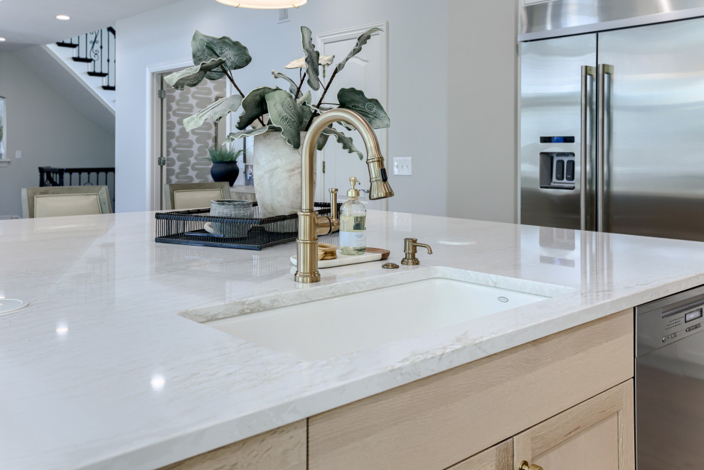 Example of a transitional light wood floor and beige floor open concept kitchen design with an undermount sink, white cabinets, quartzite countertops, multicolored backsplash, stainless steel appliances and an island