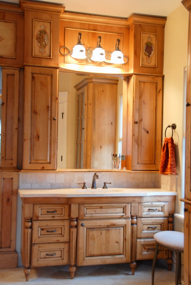 Example of a large mountain style master travertine floor and beige floor bathroom design with raised-panel cabinets, light wood cabinets, beige walls, an undermount sink and quartz countertops