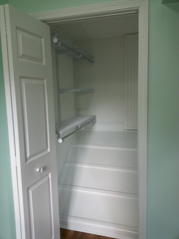 Example of a small arts and crafts gender-neutral medium tone wood floor walk-in closet design in Grand Rapids with louvered cabinets and white cabinets