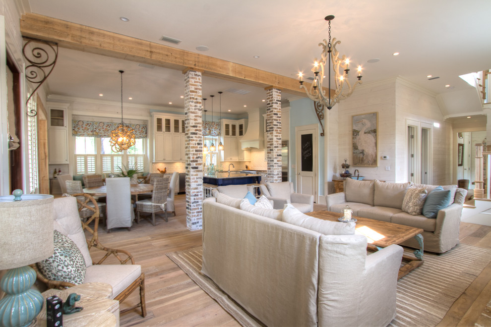 Inspiration for an expansive beach style open concept family room in Miami with white walls, light hardwood floors, a standard fireplace, a wall-mounted tv, a brick fireplace surround and beige floor.
