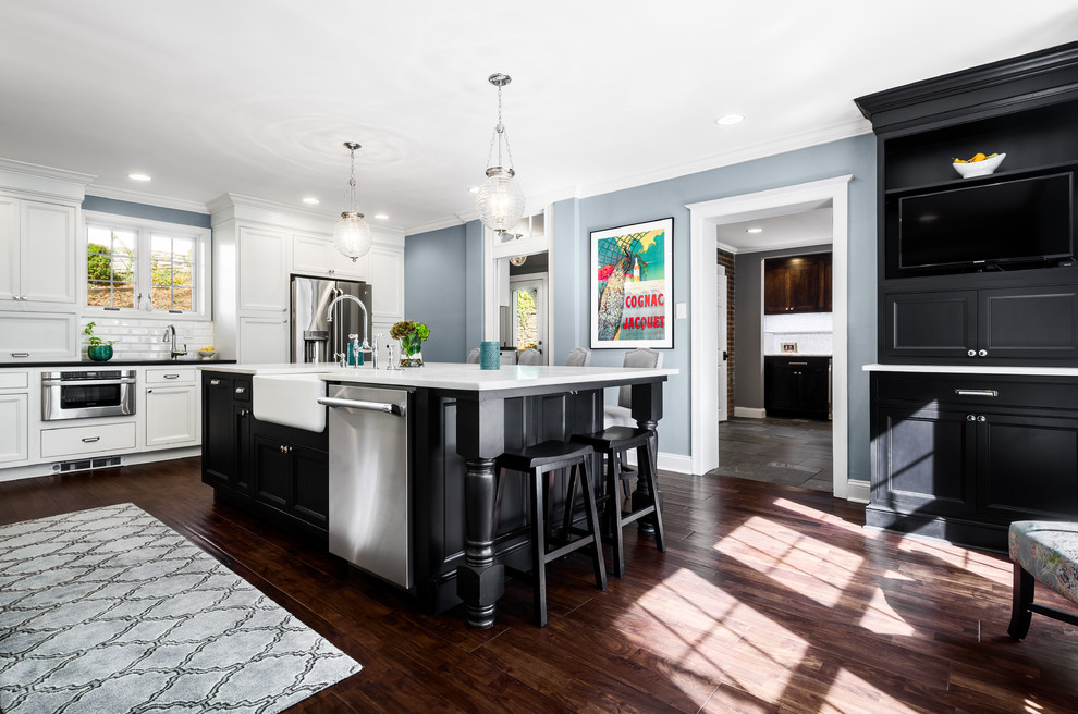 Design ideas for a large contemporary l-shaped eat-in kitchen in Philadelphia with a farmhouse sink, recessed-panel cabinets, black cabinets, marble benchtops, white splashback, subway tile splashback, stainless steel appliances, dark hardwood floors and with island.