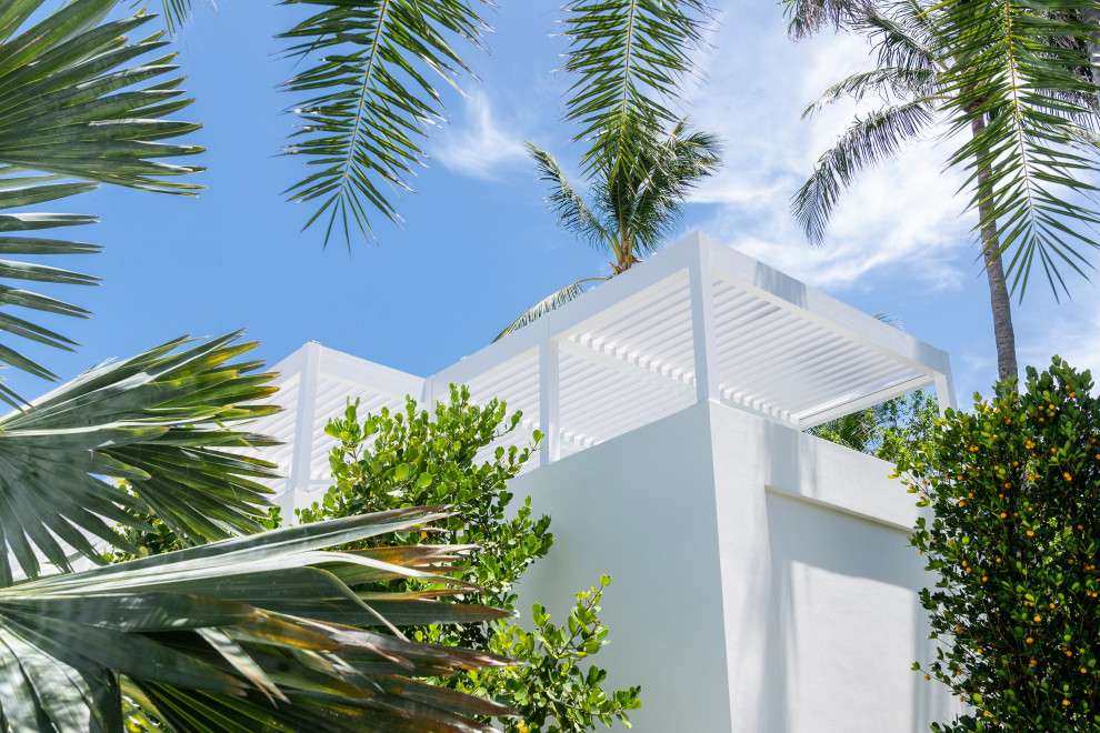 Inspiration for a large beach style two-storey concrete white house exterior in Miami with a white roof and a flat roof.