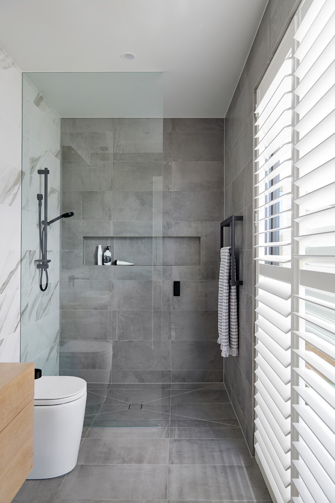 Contemporary bathroom in Other with flat-panel cabinets, medium wood cabinets, a curbless shower, a wall-mount toilet, gray tile, white tile, white walls, wood benchtops, grey floor, an open shower and brown benchtops.