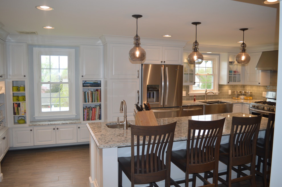 Inspiration for a large transitional u-shaped ceramic tile and gray floor enclosed kitchen remodel with a farmhouse sink, raised-panel cabinets, white cabinets, quartz countertops, gray backsplash, glass tile backsplash, stainless steel appliances and an island