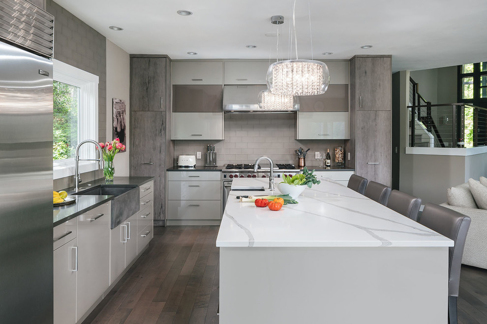 Design ideas for a mid-sized contemporary l-shaped eat-in kitchen in Portland with a farmhouse sink, flat-panel cabinets, grey cabinets, dark hardwood floors, with island, brown floor, white benchtop, quartzite benchtops, grey splashback, glass tile splashback and stainless steel appliances.