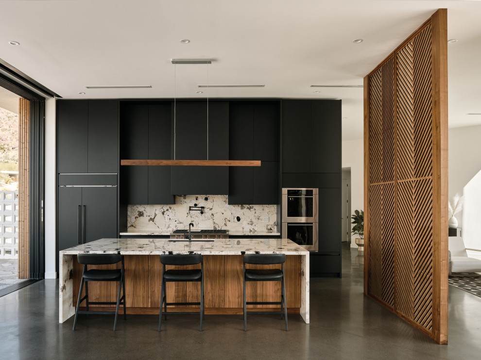 Inspiration for a contemporary single-wall open plan kitchen in Phoenix with a submerged sink, flat-panel cabinets, black cabinets, marble worktops, white splashback, marble splashback, integrated appliances, concrete flooring, an island, white worktops and grey floors.