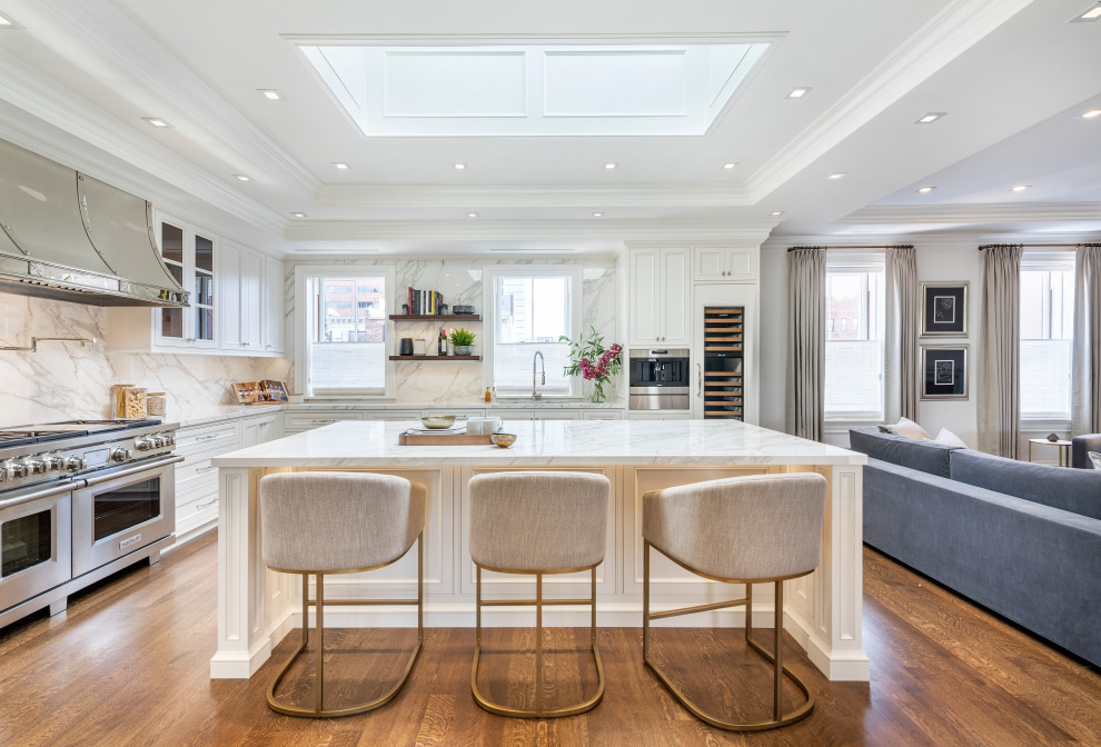This is an example of a transitional l-shaped kitchen in Boston with an undermount sink, recessed-panel cabinets, white cabinets, marble benchtops, grey splashback, stainless steel appliances, medium hardwood floors, with island, grey benchtop and vaulted.
