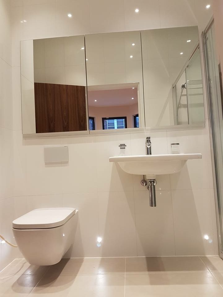 Photo of a mid-sized modern kids bathroom in London with an open shower, a wall-mount toilet, green tile, ceramic tile, white walls, ceramic floors, a wall-mount sink, beige floor and a sliding shower screen.