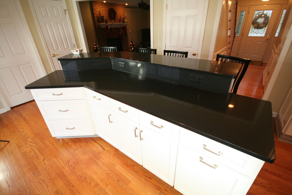 Inspiration for a mid-sized transitional l-shaped medium tone wood floor eat-in kitchen remodel with an undermount sink, recessed-panel cabinets, white cabinets, quartz countertops, beige backsplash, ceramic backsplash, white appliances and an island