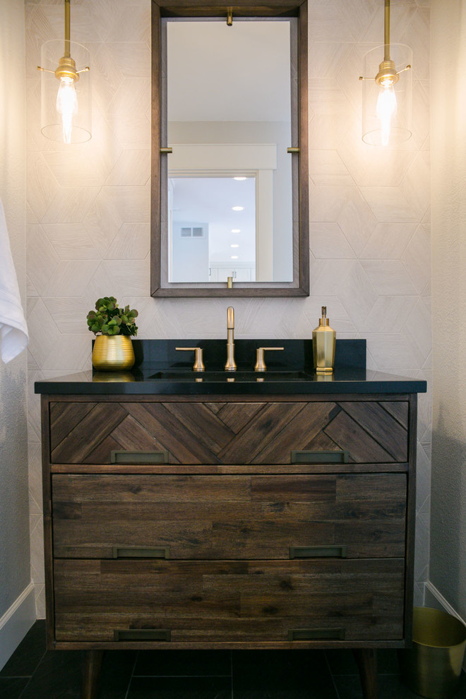 Inspiration for a mid-sized transitional powder room in Denver with flat-panel cabinets, dark wood cabinets, a one-piece toilet, gray tile, travertine, an undermount sink, engineered quartz benchtops and black benchtops.