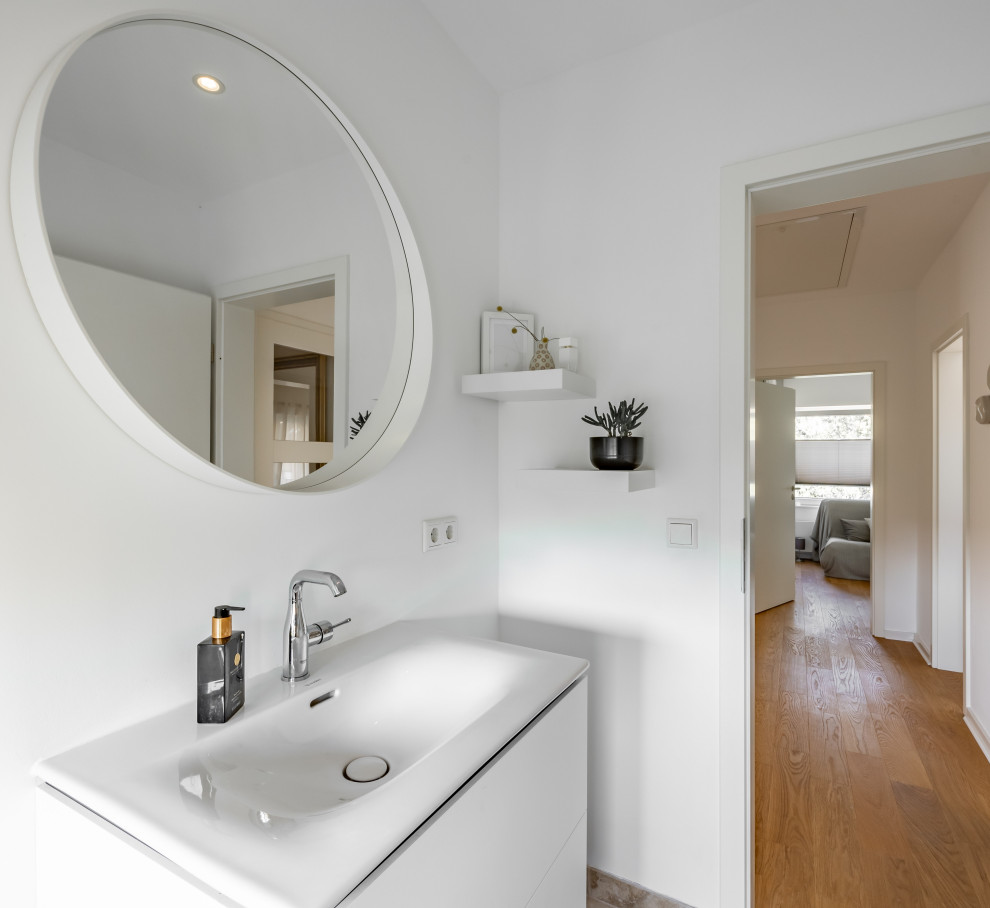 Immagine di un bagno di servizio minimal di medie dimensioni con ante lisce, ante bianche, lavabo integrato, top in superficie solida e mobile bagno sospeso