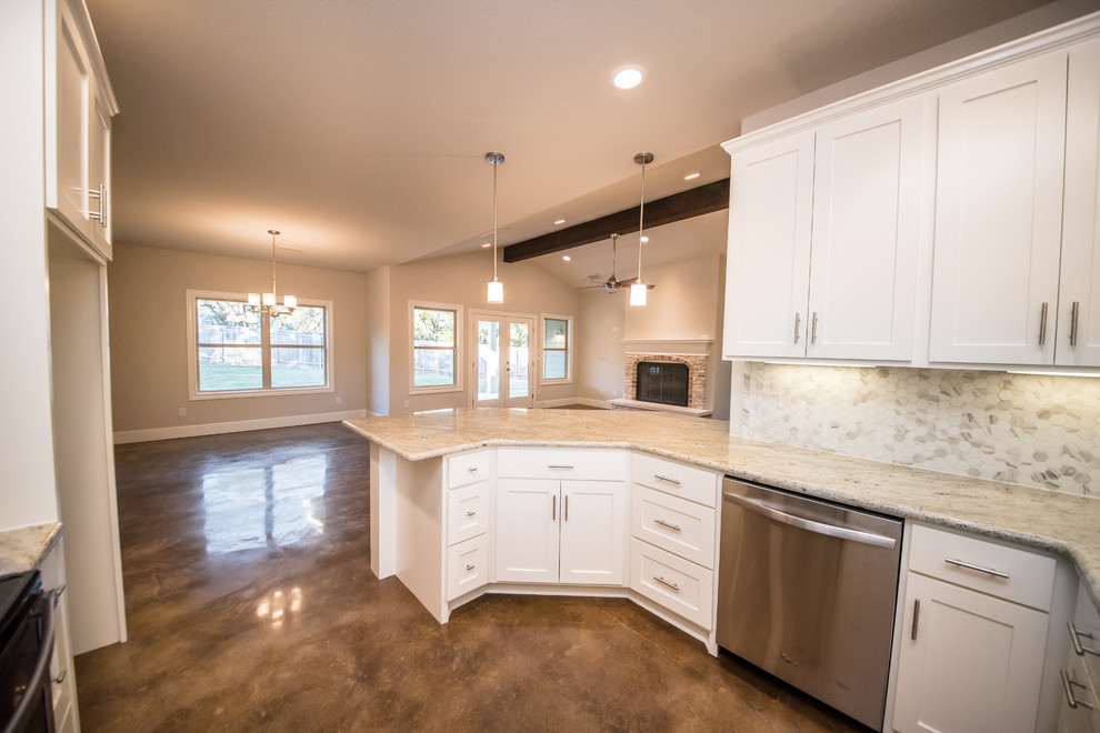 Inspiration for a mid-sized arts and crafts u-shaped open plan kitchen in Austin with a double-bowl sink, white cabinets, granite benchtops, beige splashback, ceramic splashback, stainless steel appliances, concrete floors, shaker cabinets and a peninsula.