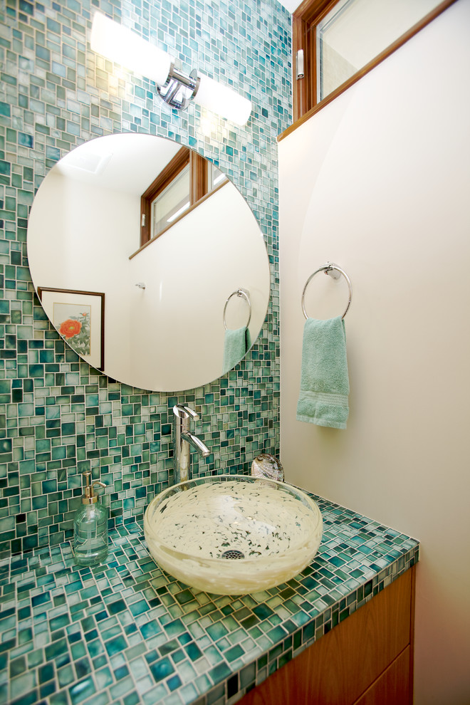 Inspiration for a mid-sized contemporary powder room in Orange County with a vessel sink, flat-panel cabinets, medium wood cabinets, tile benchtops, green tile, mosaic tile and white walls.