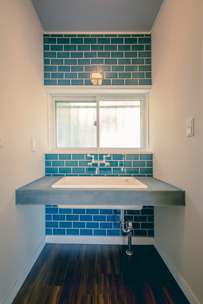 Inspiration for a small scandinavian powder room in Other with beaded inset cabinets, white cabinets, concrete benchtops, grey benchtops, a one-piece toilet, blue tile, subway tile, white walls, vinyl floors, an undermount sink and brown floor.