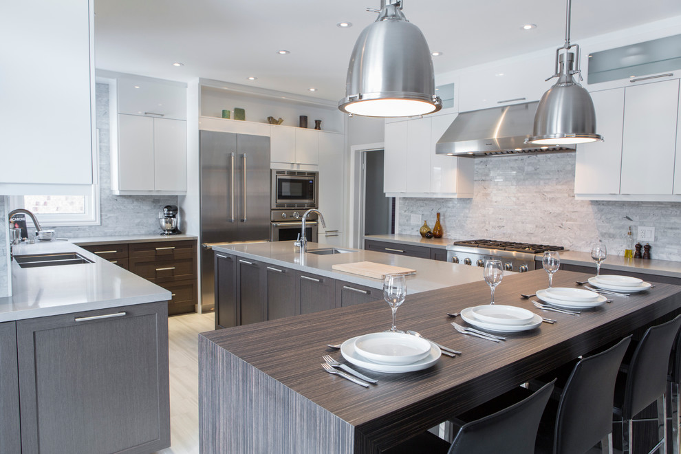 This is an example of a contemporary kitchen in Toronto with an undermount sink, quartz benchtops, stone tile splashback and stainless steel appliances.
