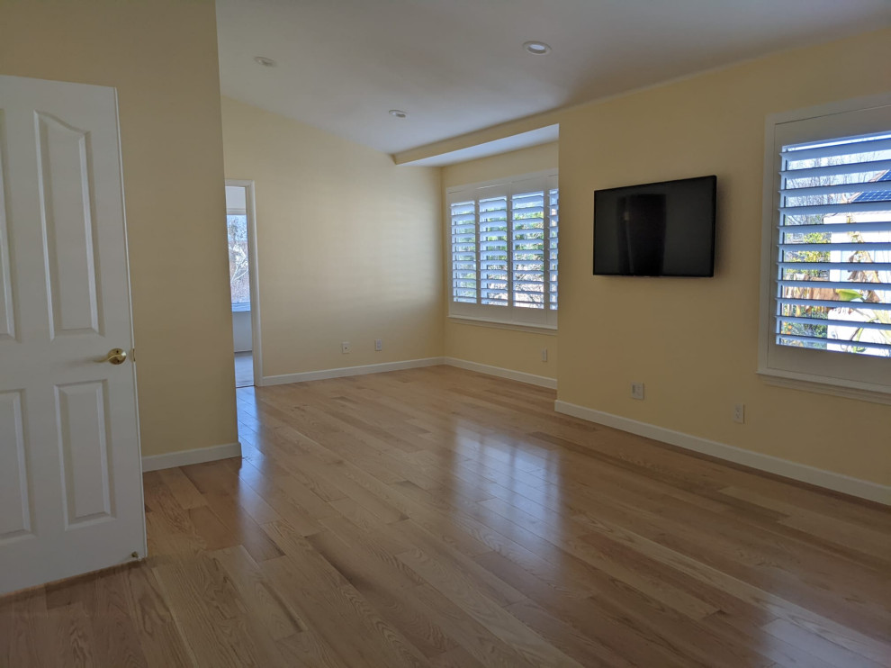 Repräsentatives Wohnzimmer mit gebeiztem Holzboden, TV-Wand, orangem Boden und gewölbter Decke in San Francisco