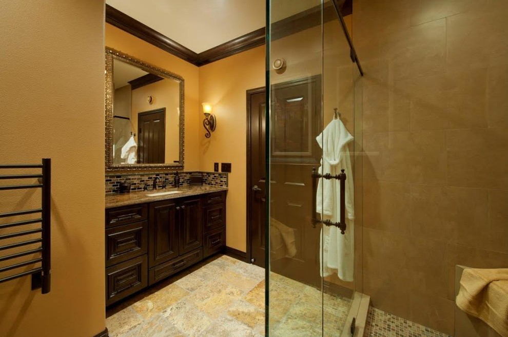 This is an example of a mid-sized transitional 3/4 bathroom in Seattle with recessed-panel cabinets, dark wood cabinets, an alcove shower, a one-piece toilet, beige tile, black tile, brown tile, gray tile, matchstick tile, beige walls, slate floors, an undermount sink and granite benchtops.