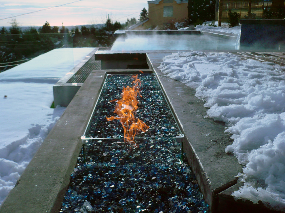 This is an example of a large contemporary sloped formal garden in Vancouver with a fire feature.
