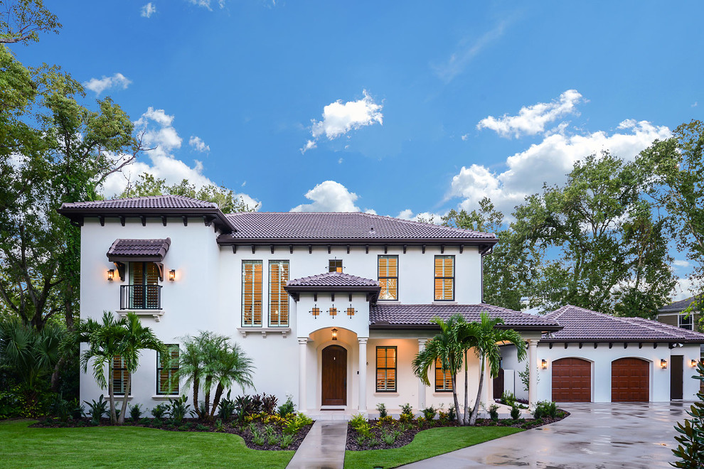 Photo of a large mediterranean two-storey stucco white house exterior in Tampa with a hip roof and a tile roof.