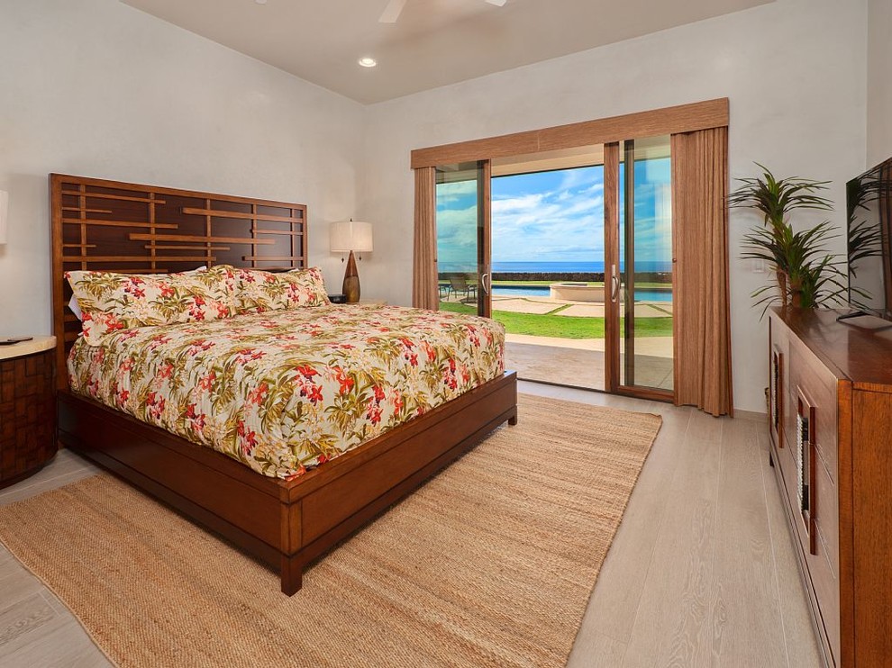 Inspiration for a mid-sized tropical master bedroom in Hawaii with white walls, light hardwood floors, no fireplace and beige floor.
