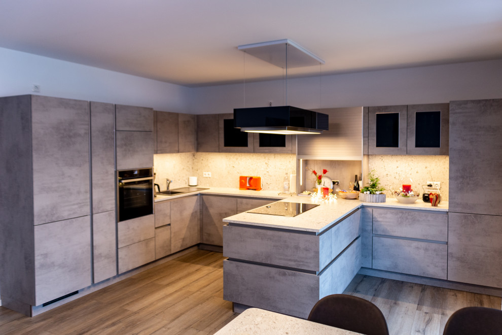 Küche in U-Form mit Einbauwaschbecken, Glasfronten, grauen Schränken, Arbeitsplatte aus Holz, Küchenrückwand in Grau, Rückwand aus Holz, schwarzen Elektrogeräten, Keramikboden, Halbinsel, braunem Boden, grauer Arbeitsplatte und Tapetendecke in Dusseldorf