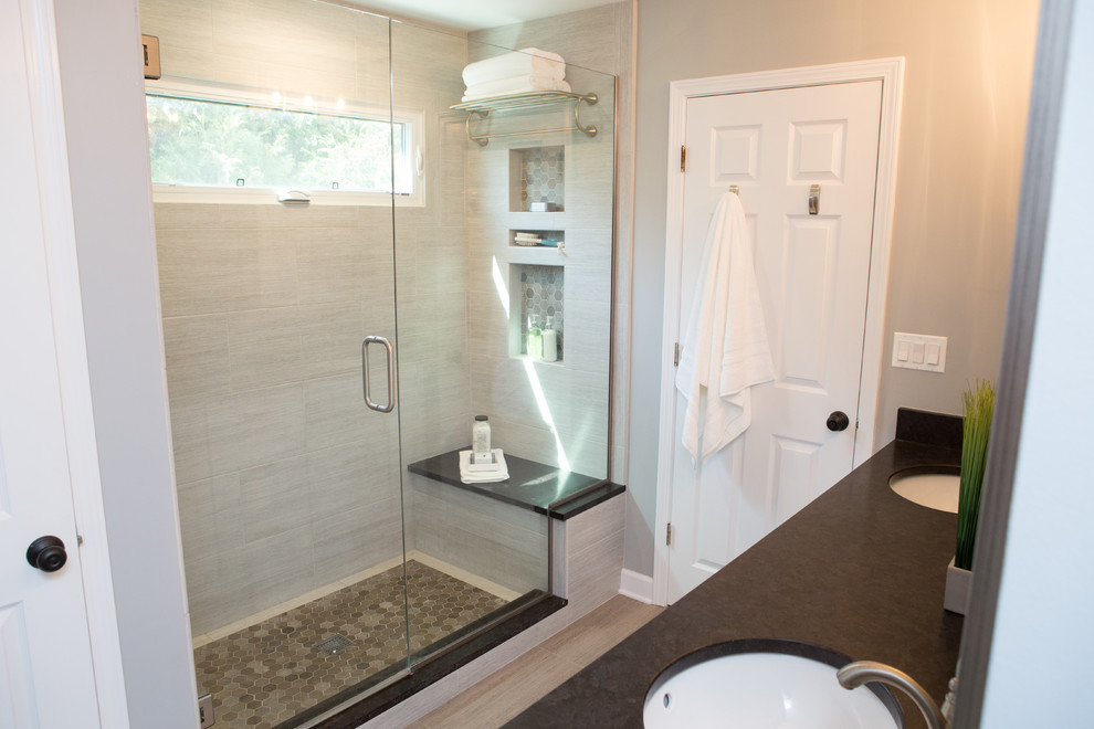Photo of a mid-sized transitional master bathroom in Chicago with recessed-panel cabinets, an alcove shower, a two-piece toilet, gray tile, porcelain tile, grey walls, porcelain floors, an undermount sink, granite benchtops, grey floor and a hinged shower door.
