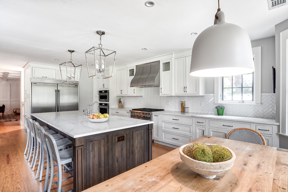 Design ideas for an expansive traditional galley eat-in kitchen in New York with a farmhouse sink, beaded inset cabinets, white cabinets, quartzite benchtops, white splashback, subway tile splashback, stainless steel appliances, medium hardwood floors, with island and white benchtop.