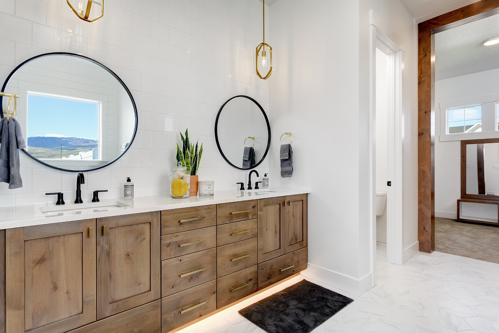This is an example of a large country master bathroom in Boise with shaker cabinets, medium wood cabinets, a freestanding tub, an alcove shower, white tile, porcelain tile, white walls, marble floors, an undermount sink, engineered quartz benchtops, white floor, an open shower and white benchtops.