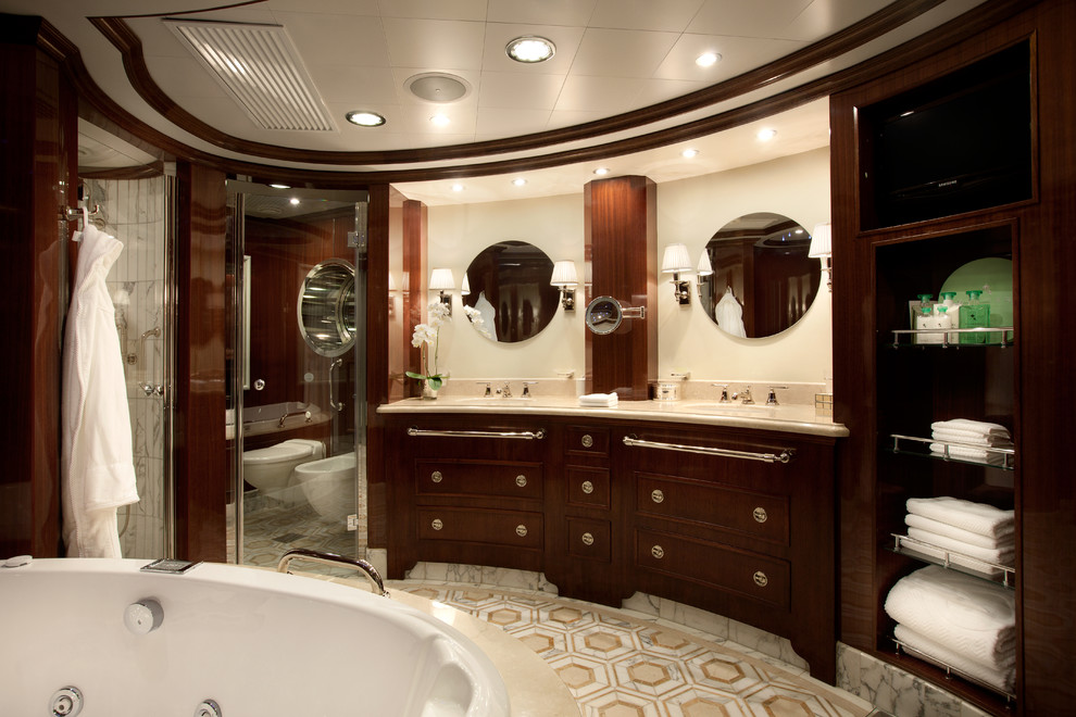 This is an example of a traditional master bathroom in Dallas with furniture-like cabinets, brown cabinets, a drop-in tub, an alcove shower, a bidet, mosaic tile floors, an undermount sink, marble benchtops, beige floor, a hinged shower door and beige benchtops.