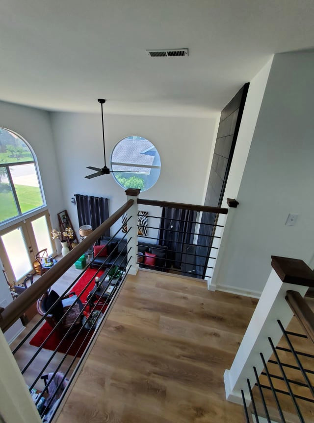 Expansive classic mezzanine living room in Other with white walls, vinyl flooring, a standard fireplace, a tiled fireplace surround and brown floors.