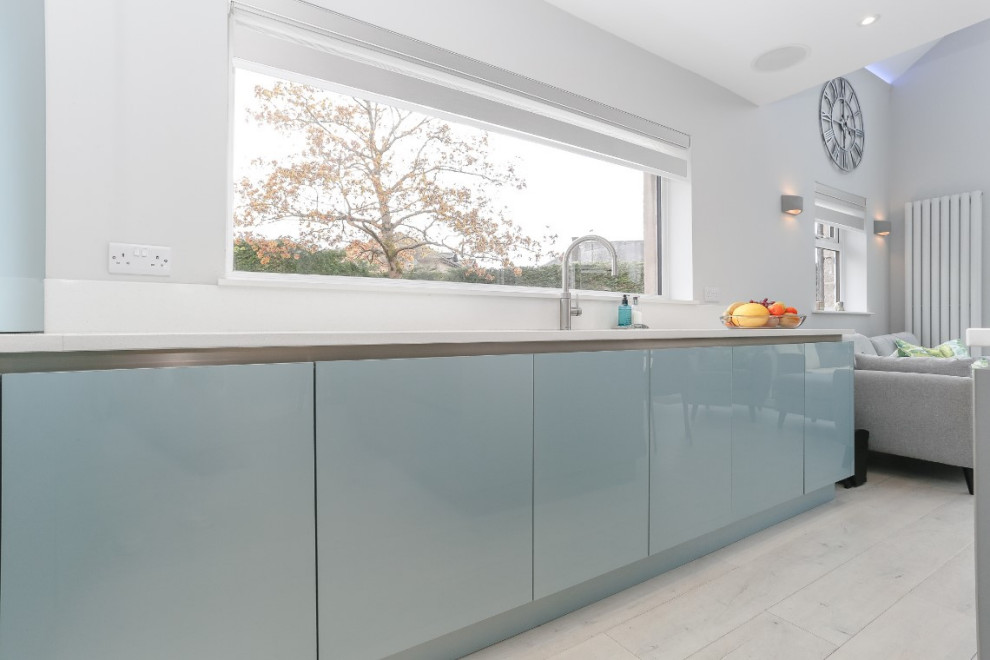 Inspiration for a mid-sized modern u-shaped eat-in kitchen in Glasgow with flat-panel cabinets, blue cabinets, black appliances, with island, grey floor, white benchtop and an integrated sink.