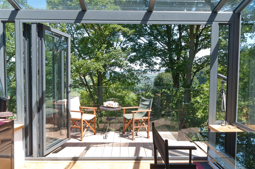 Photo of a mid-sized contemporary sunroom in Manchester with a glass ceiling.
