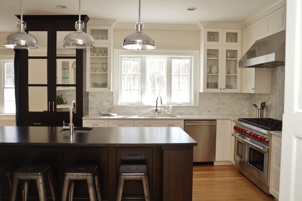 Photo of a mid-sized industrial l-shaped eat-in kitchen in Boston with an undermount sink, white cabinets, grey splashback, stainless steel appliances, light hardwood floors, with island, subway tile splashback, shaker cabinets, laminate benchtops, brown floor and white benchtop.