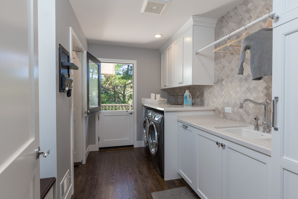 Inspiration for a mid-sized transitional galley dedicated laundry room in San Francisco with an undermount sink, shaker cabinets, white cabinets, quartz benchtops, grey walls, dark hardwood floors, a side-by-side washer and dryer and brown floor.