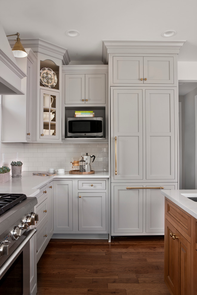 This is an example of a transitional u-shaped kitchen in Detroit with beaded inset cabinets, grey cabinets, quartz benchtops, white splashback, subway tile splashback, stainless steel appliances and light hardwood floors.