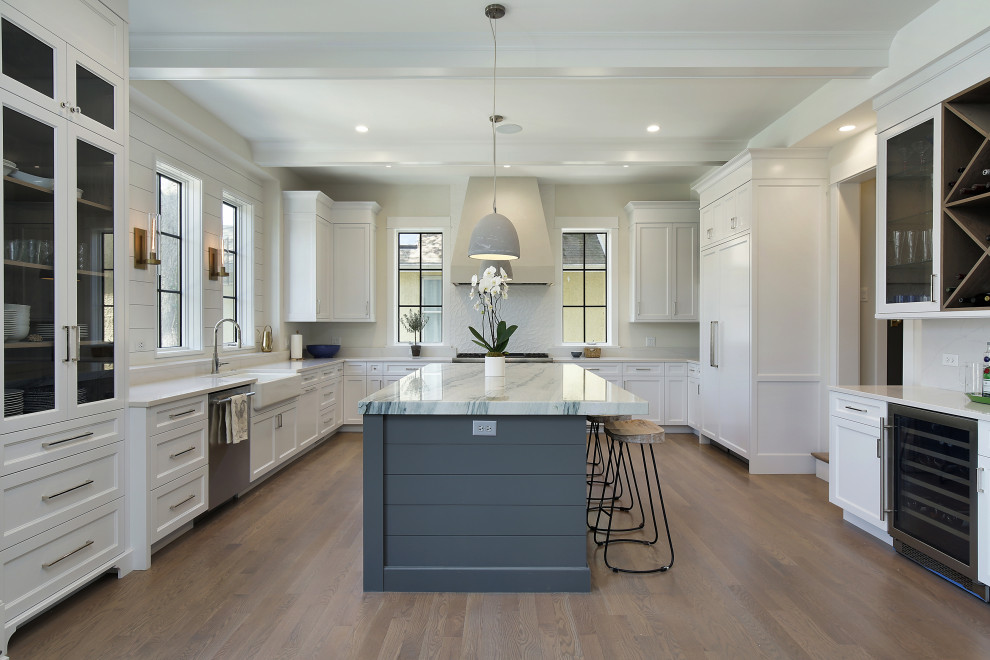 Design ideas for a transitional u-shaped separate kitchen in Chicago with a farmhouse sink, recessed-panel cabinets, white cabinets, white splashback, panelled appliances, medium hardwood floors, with island, brown floor, white benchtop and exposed beam.