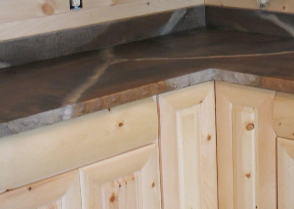 Medium tone wood floor kitchen photo with light wood cabinets, concrete countertops and stainless steel appliances