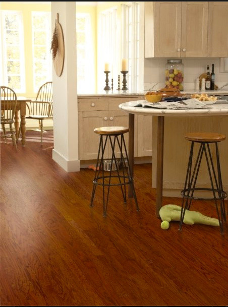 Example of a mid-sized transitional l-shaped medium tone wood floor enclosed kitchen design with shaker cabinets, light wood cabinets and granite countertops